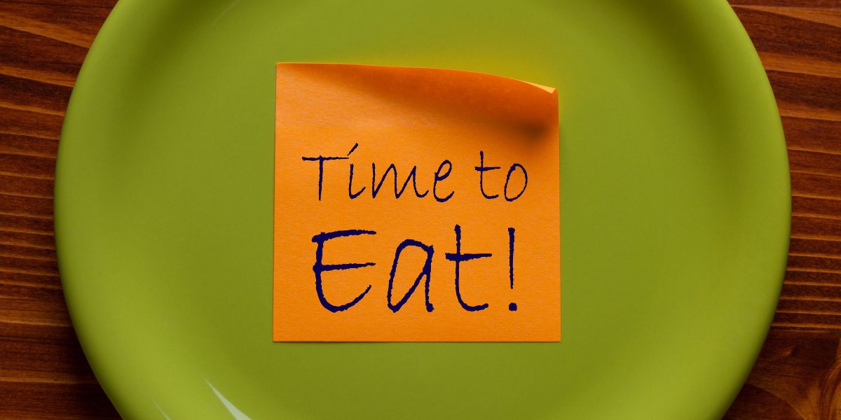 緑の皿に「Time to Eat!」と書かれた付箋が貼られた写真。食事のタイミングを決めて続けるイメージ(40〜50代向け)
